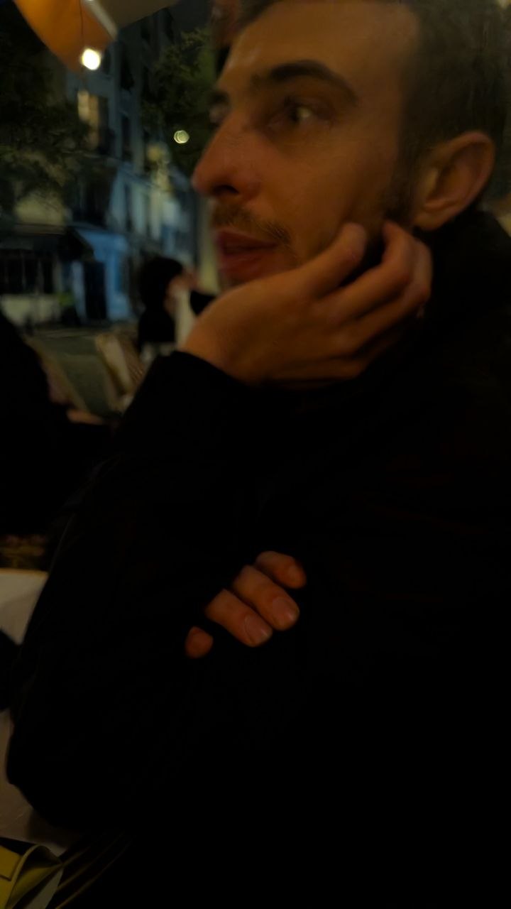 Tibo de profil, main sur le menton, dans une rue de Paris la nuit